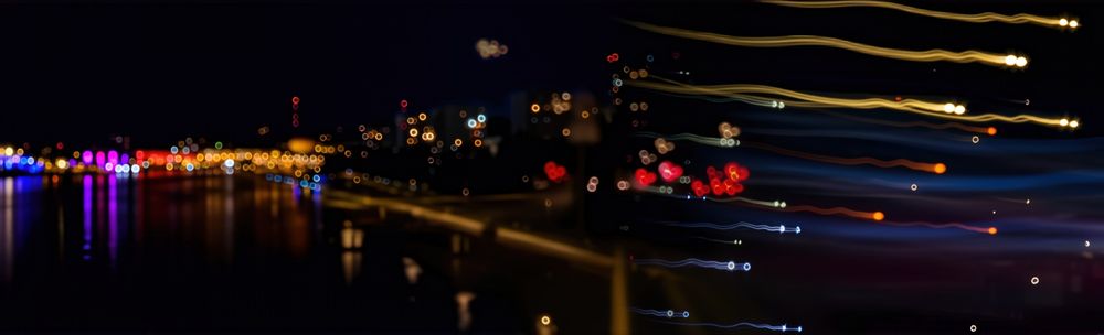A blend of 4 images of a nighttime cityscape taken with a pinhole lens. Horizontal view of the city center on the left, followed by residential buildings, a series of red dots resembling little hearts, followed by little "swimmers" ;-), light trails looking for a target.