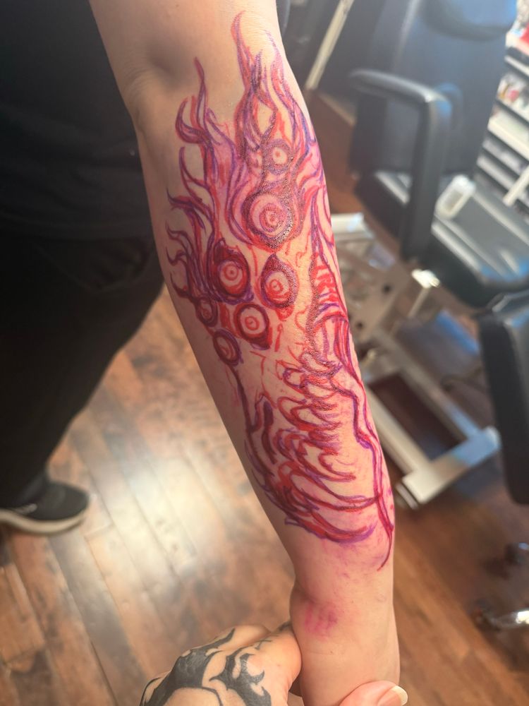 A photograph of the the original sketch of the tattoo, done in red sharpie marker on skin.