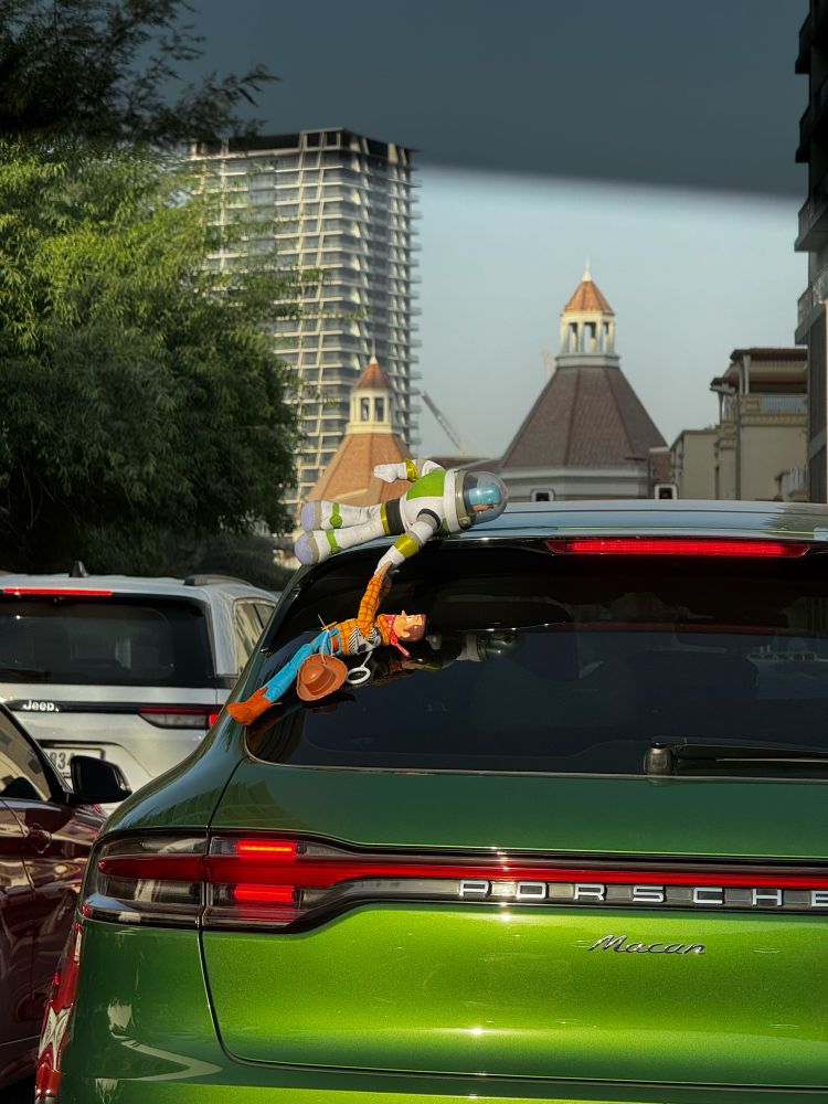 A green Porsche car with characters from Toy Story (Buzz Lightyear and Woody) hanging on top of the car. Recreating an iconic scene from the movie.