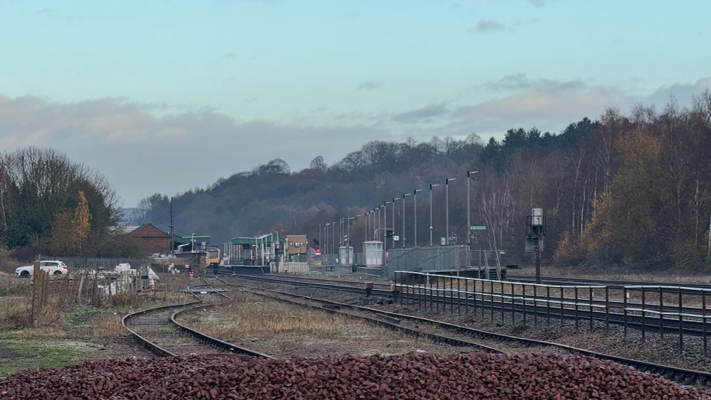 View of Chesterfield railway station from a goods yard looking north over the top of a pile of ballast waiting to be used.