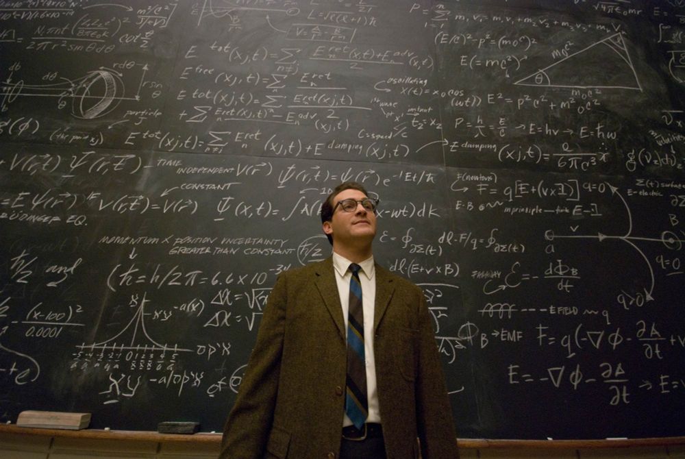 Michael Stuhlbarg as Larry Gopnik from the film A Serious Man standing in front of a blackboard covered in maths equations.  