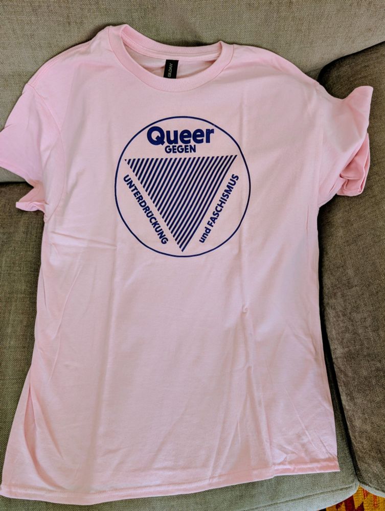 A pink t-shirt with a text: queer gegen unterdrucknung und faschismus.