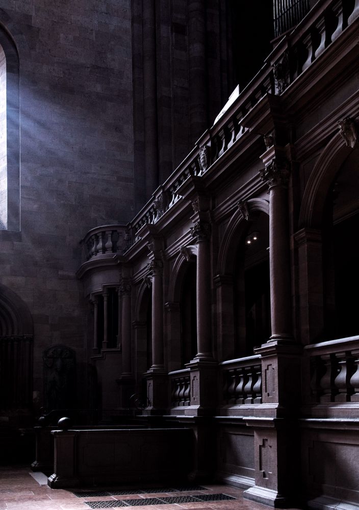 A dark cathedral with sun coming through a high window