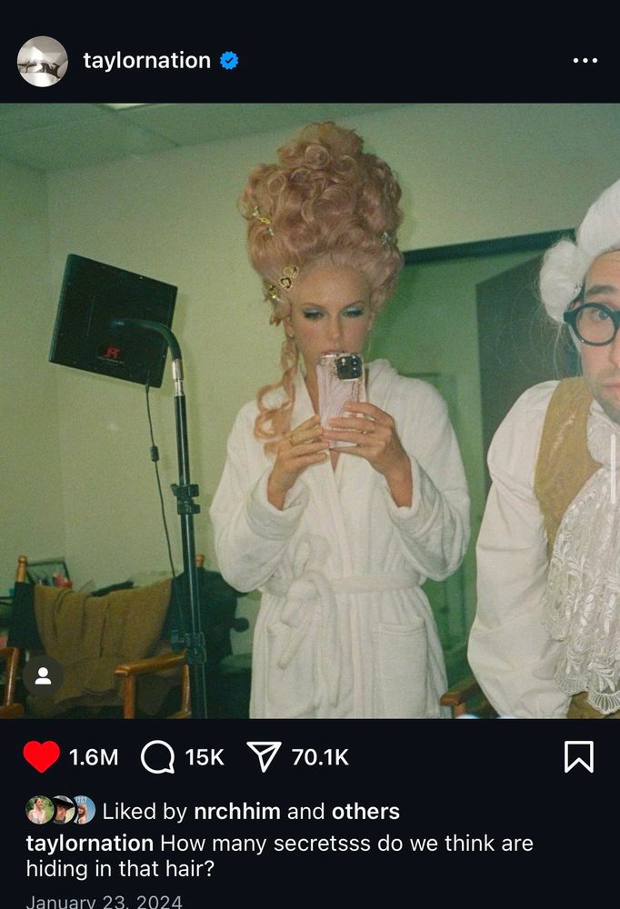 Screenshot of Taylor Nation instagram of Taylor Swift and Jack Antonoff in large powdered wigs and white robes. The caption reads “How many secretsss do we think are hiding in that hair?”