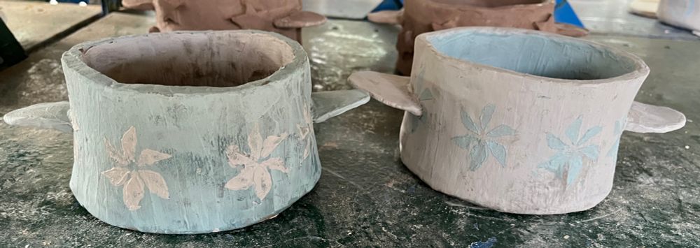 2 Ceramic small round pots made of blue and gray clay. Pot 1 is blue (will fire green) with gray (will fire bright blue) pinwheels. Pot 2 is gray (will fire bright blue) with blue (will fire green) pinwheels. The pots have not been fired or glazed.