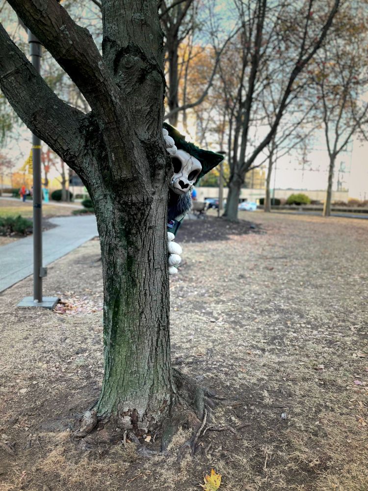 Green and bone colored skullbeast peeking out from behind a tree