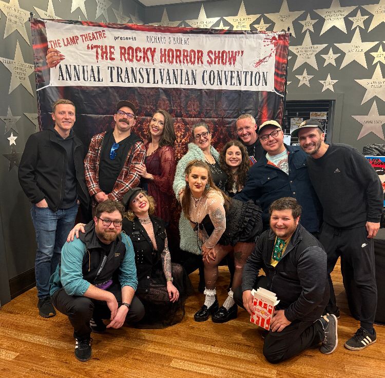 The whole gang posing in front of the Rocky Horror Show Annual Transylvanian Convention banner 