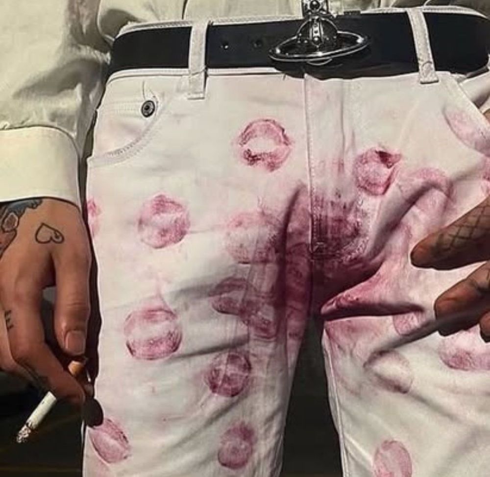 Red lipstick stains all over white pants specifically around the crotch, while the person is holding a cigarette in one hand