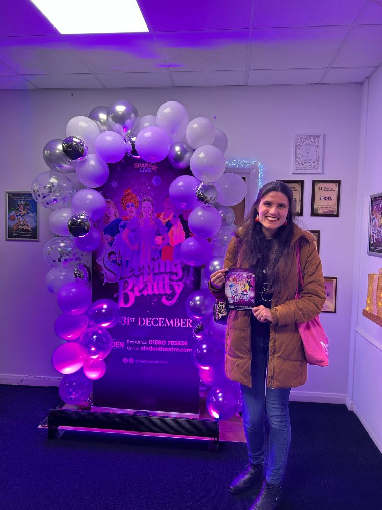 Kat Masterson standing next to the ‘Sleeping Beauty’ banner and balloon arrangement at the Sinden Theatre, Tenterden