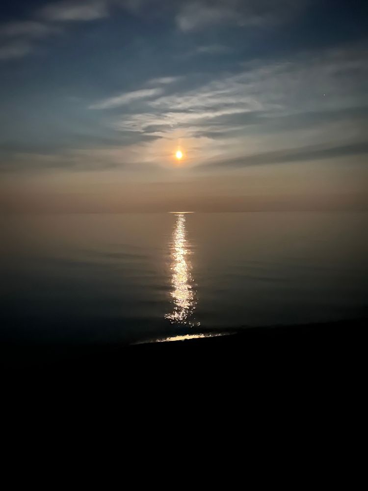Photo of moonrise over Lake Superior.   The moon light is reflecting off the lake in a line all the way to the shore.