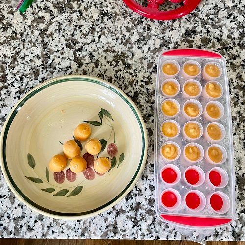 Ice cube tray full of apricot shiroan next to a few already on a plate.