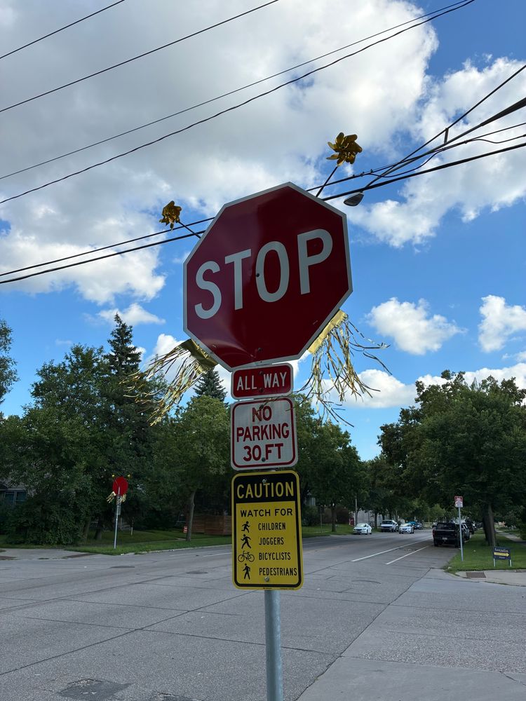 A stop sign with gold fringes and pinwheels attached. 