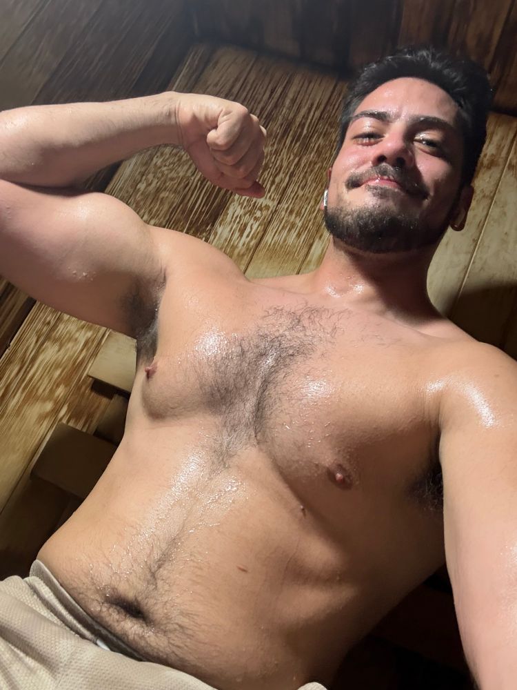 Seismic flexing his arm in a wood paneled sauna, sweating