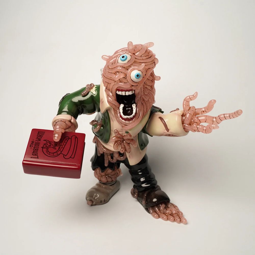 Figuring: a worm guy... he's made of worms. Worm hands, worm head, eyeballs kinda rolling around in the worms, open mouth... the mouth is normal. Still has on a tan shirt and green jacket. Worms are leaking out of the black pants. A shoe is missing, worms coming out.

Somehow this figure is holding a red hardcover book out. Seems important to them. Says "The Lambton Worm" with an illustration of a demonic worm. 