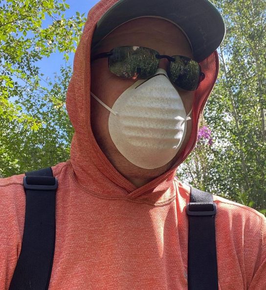 Picture of me, wearing a sun shirt and mask (and other PPE) as I set up a drip station