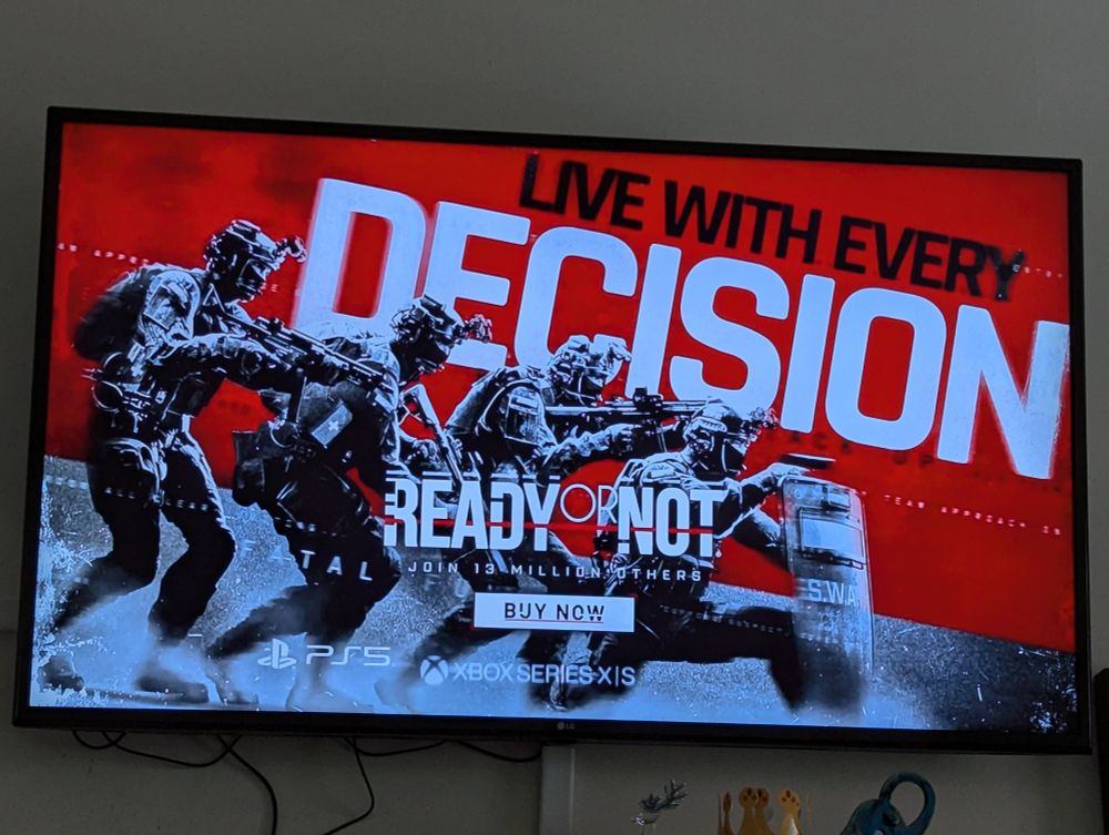 The end screen on a commercial for the video game Ready or Not, which depicts characters from the game, SWAT police officers, lined up with guns drawn behind another officer kneeling and holding a shield under the words "Live With Every Decision"