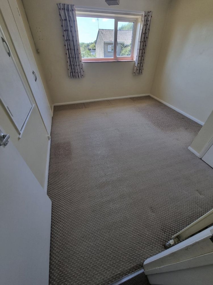 A photo of an empty second bedroom/study with faded carpet