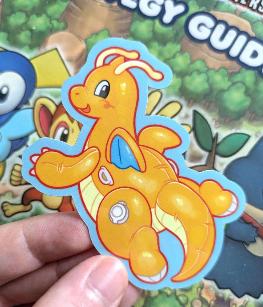 Sticker of a cute, shiny Dragonite pooltoy smiling at the viewer.