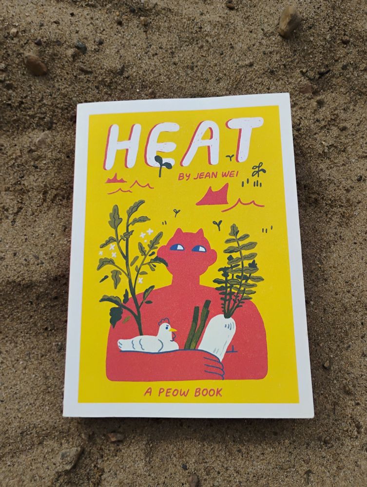 A photo of the cover of the book Heat by Jean Wei. It depicts a fire demon, large and red with tiny horns. They hold a chicken and several plants in their arms.
