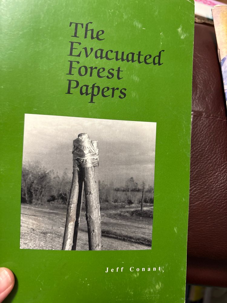 Green book of poetry titled “The Evacuated Forest Papers” by Jeff Conant