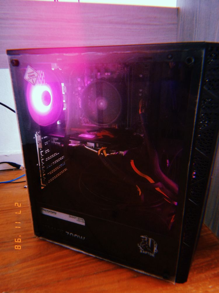 A picture of my desktop pc tower, it has a glass side that shows its cabling and components, the pink leds are on and fans working.
