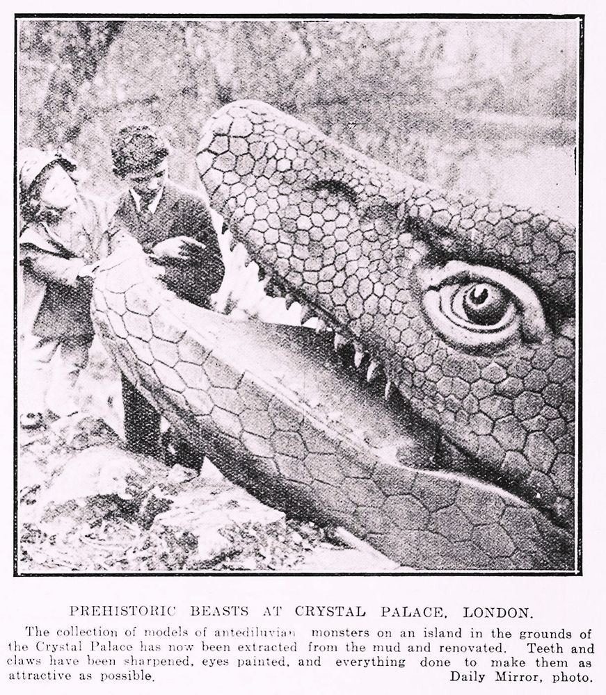 Black and white scanned newspaper photo . A smartly dressed boy and girl study a fresh looking Crystal Palace Mosasaurus. The lake water level appears non-existent. The caption:

“The collection of models of antediluvian monsters on an island in the grounds of the Crystal Palace has now been extracted from the mud and renovated. Teeth and claws have been sharpened, eyes painted, and everything done to make them as attractive as possible.”