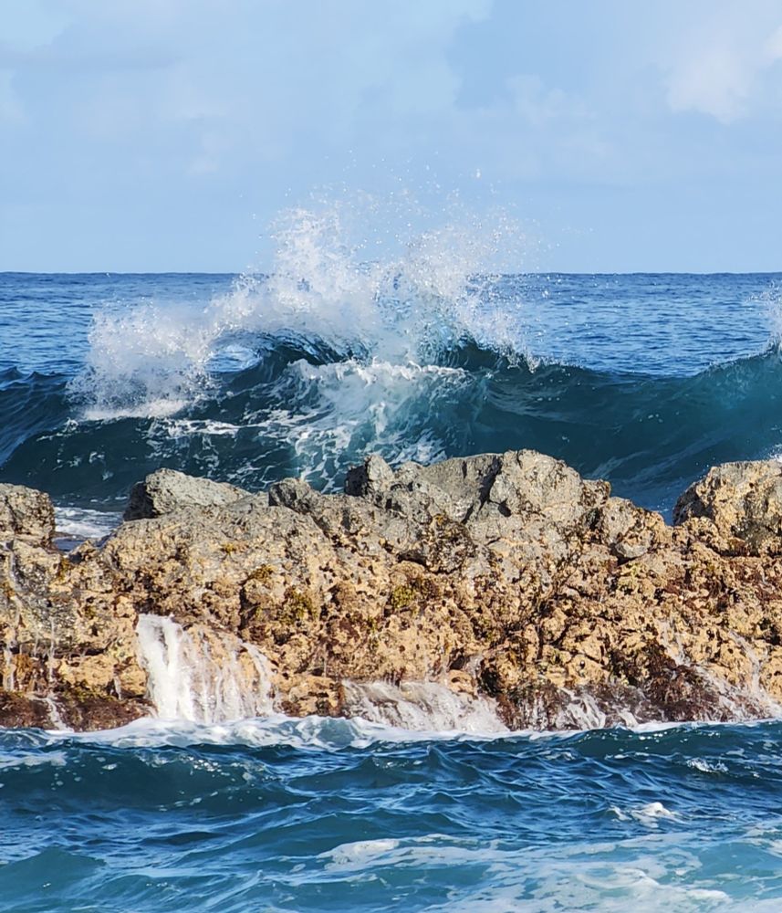 Wave breaking over rocks.  Top of break has nice curl and also splashes in several directions.