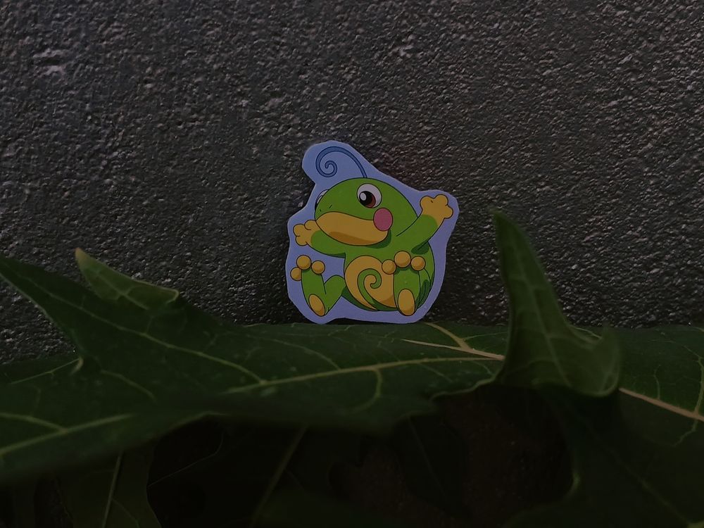 a cardboard "politoed" sitting on a papaya leaf.