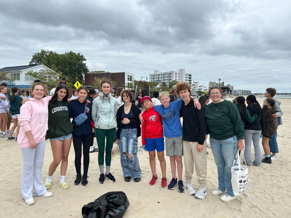 A group of students gathered on the beach and smiling at the camera