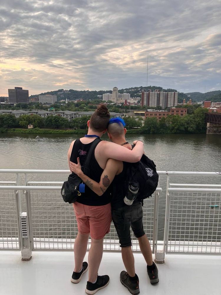Dusty and Zulas embracing one another looking out towards Pittsburgh's North Shore over the Allegheny river