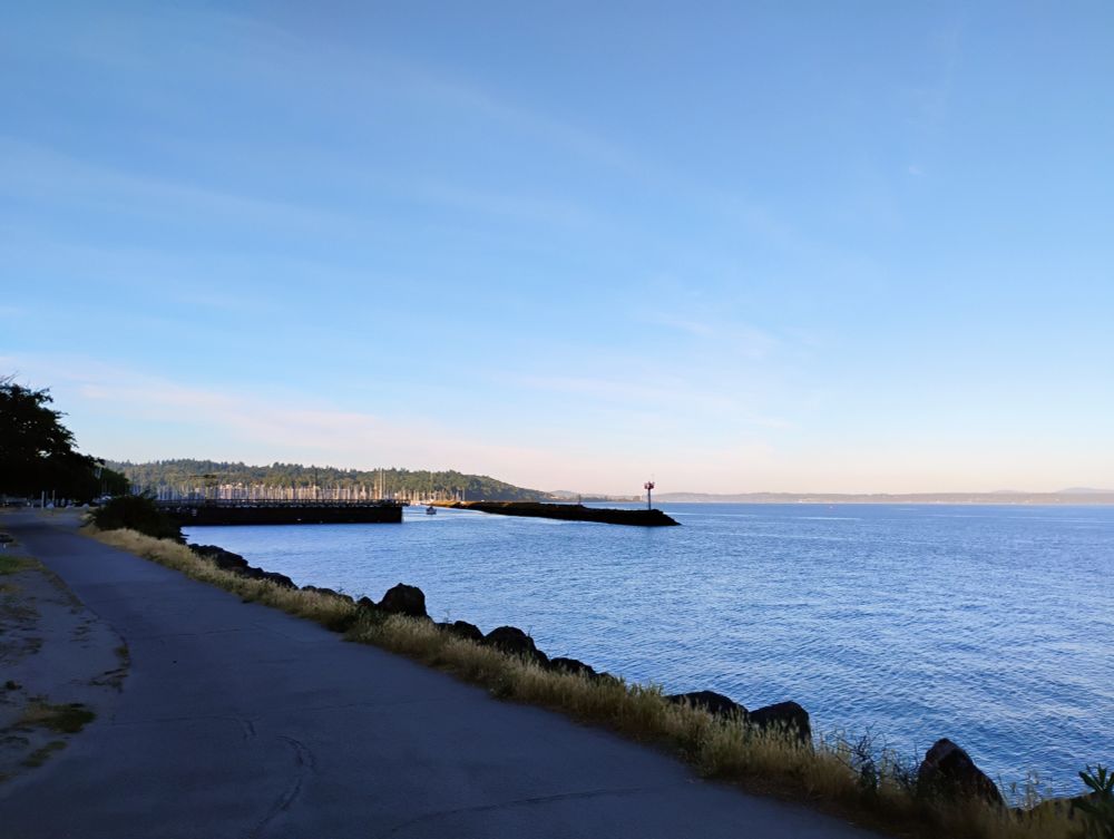 Photo (1 of 3 pano shot) of view from Golden Gardens park in Seattle, overlooking the water with blue skies in the distance