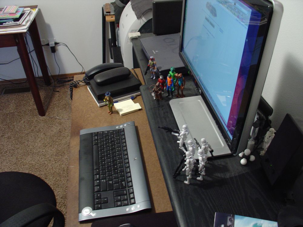 Dual-OS computer setup, running Windows on main screen and macOS (back then it was called Mac OS X) on Macbook, with lots of SW action figures in various poses on desk, things hanging on the wall, etc.