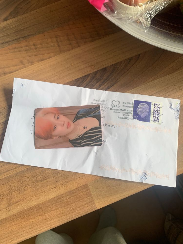 A photocard of Jimin sitting on top of a beaten up envelope 
