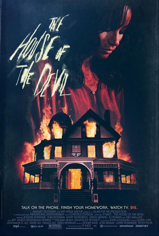 A dark Victorian-style house engulfed in flames against a black background; the title ‘The House of the Devil’ appears above in stark white lettering,