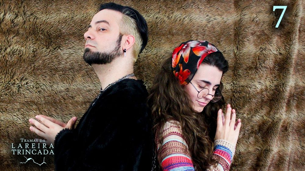 Gabiru e Bruna, um de costas para o outro. Gabiru, à esquerda, veste uma roupa preta que perde a forma na escuridão, e olha para cima solenemente, com as mâos à frente do peito, tocando as pontas dos dedos de uma na outra. Bruna faz uma pose parecida, com os dedos meio desencontrados, mas olha para baixo com os olhos fechados. Ela usa óculos, um lenço florido e um suéter colorido em tons de marrom, azul e rosa.
O fundo atrás é como a pele de um animal estendida, marrom.