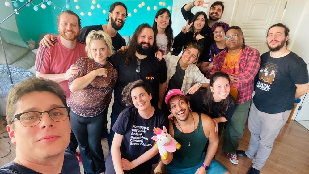 Selfie pós live, com todo mundo que estava no final sorrindo para câmera apesar do cansaço: Lucas em primeiro plano, tirando a foto, e atrás dele, amontoados na sala-estúdio: Aran, Nani, Henrique, Tuzão, Fai, Seh, Red, Lenny, Gabi, Nico, Gabiru, Clarice, Thiago e Alex Manso.