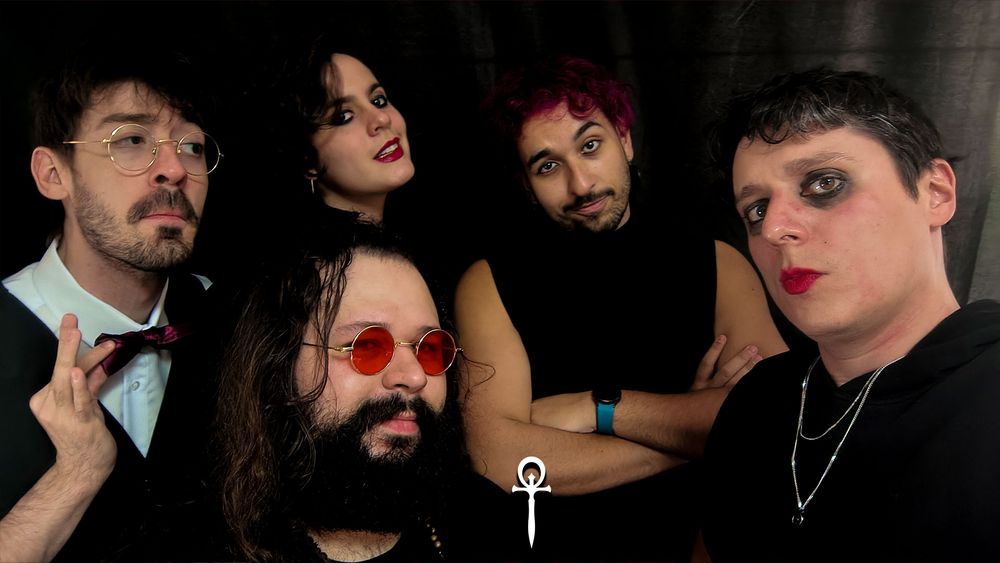 Julio, Fai, Tuzão, Seh e Luc, lado a lado. Todos vestidos de preto, em plano médio, olhando para a câmera... Vampiros da noite! E o símbolo de Vampiro: a Máscara no centro, em baixo, pequeno, em branco.