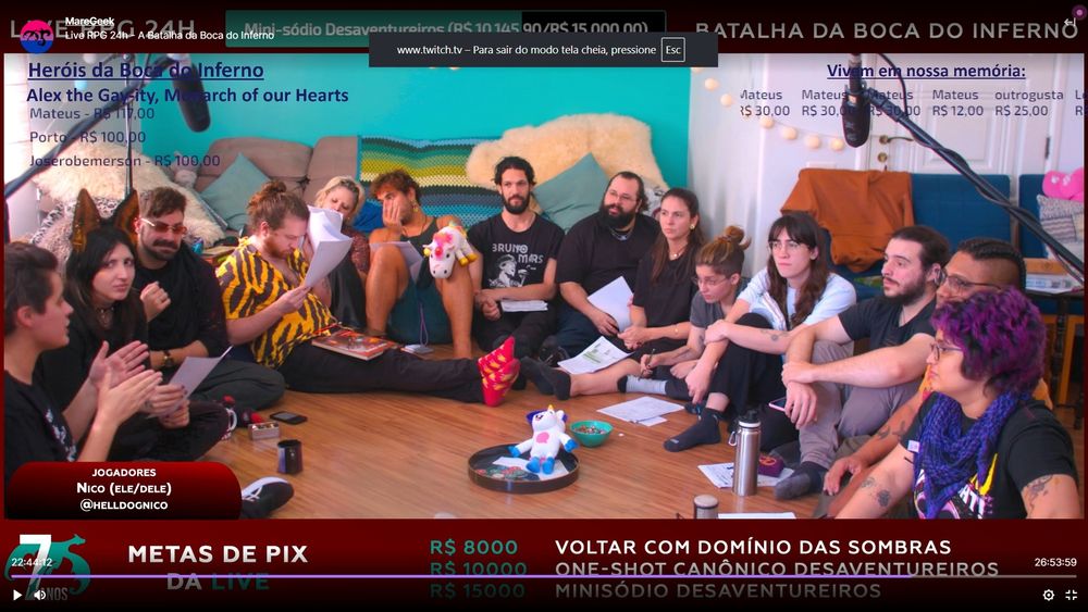 Um screenshot da live na manhã de domingo: a mesa foi retirada, e todos os jogadores estão em roda sentados no chão, conversando ou olhando suas fichas: Fai, Nico, Gabiru, Aran, Nani, Seh, Henrique, Tuzão, Gabi, Lenny, Red, Alex Manso, Thiago, Clarice.