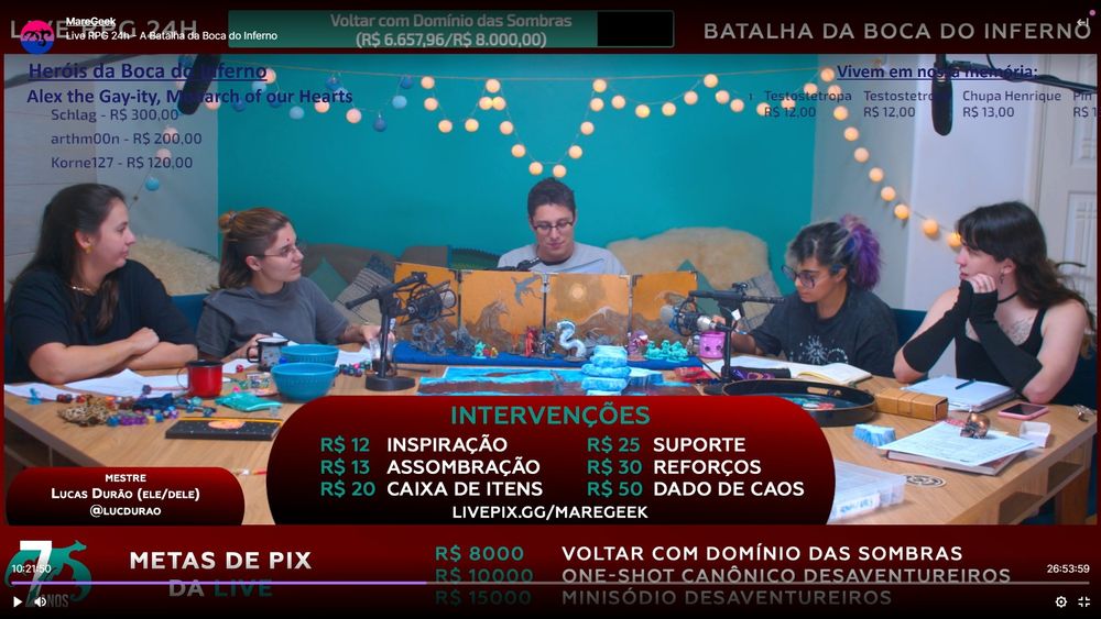 Um screenshot da live: Lucas no centro da mesa, atrás de seu escudo de mestre. À esquerda, Gabi e Lenny. À direita, Hita e Red.