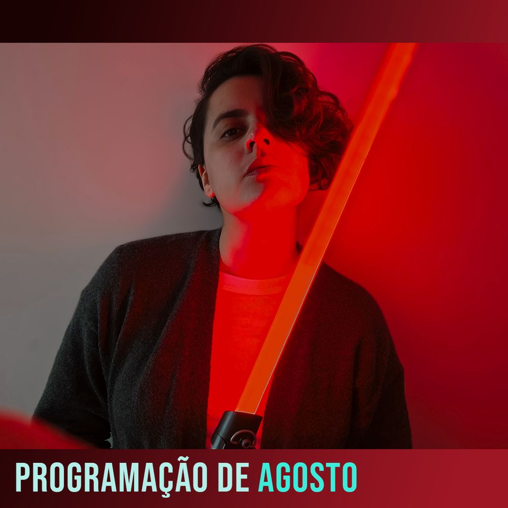 Foto de Fai, de queixo erguido, segurando um sabre de luz vermelho. Na moldura também vermelha da foto, o letreiro em azul-piscina: "programação de agosto"