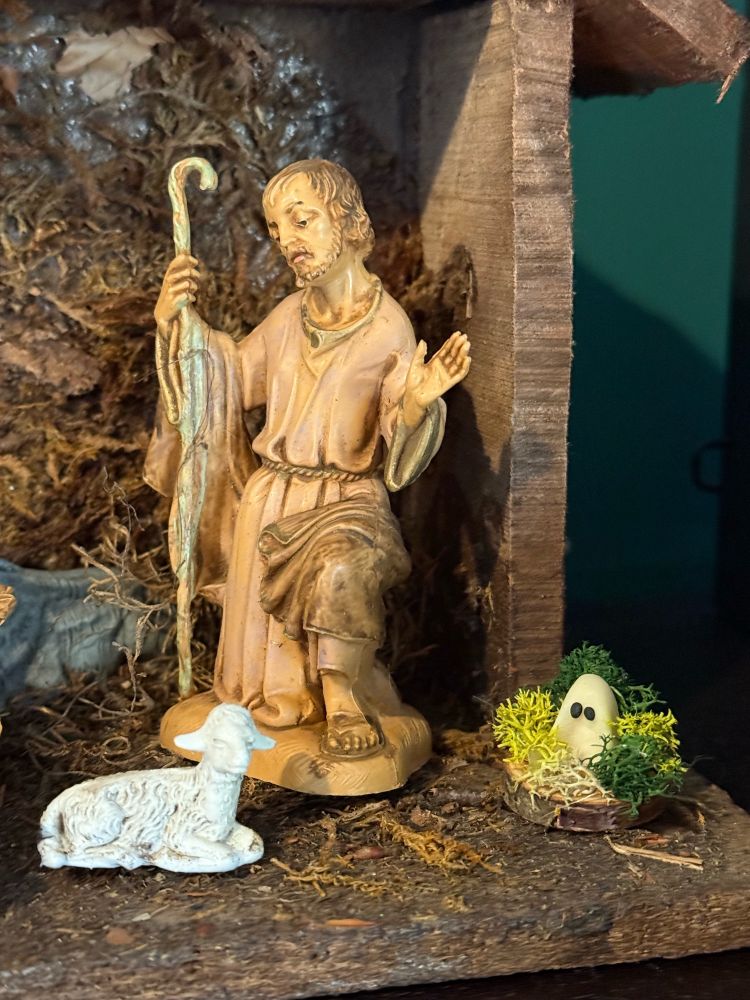 Closeup of nativity scene with shepherd, lamb, and a tiny ghost.