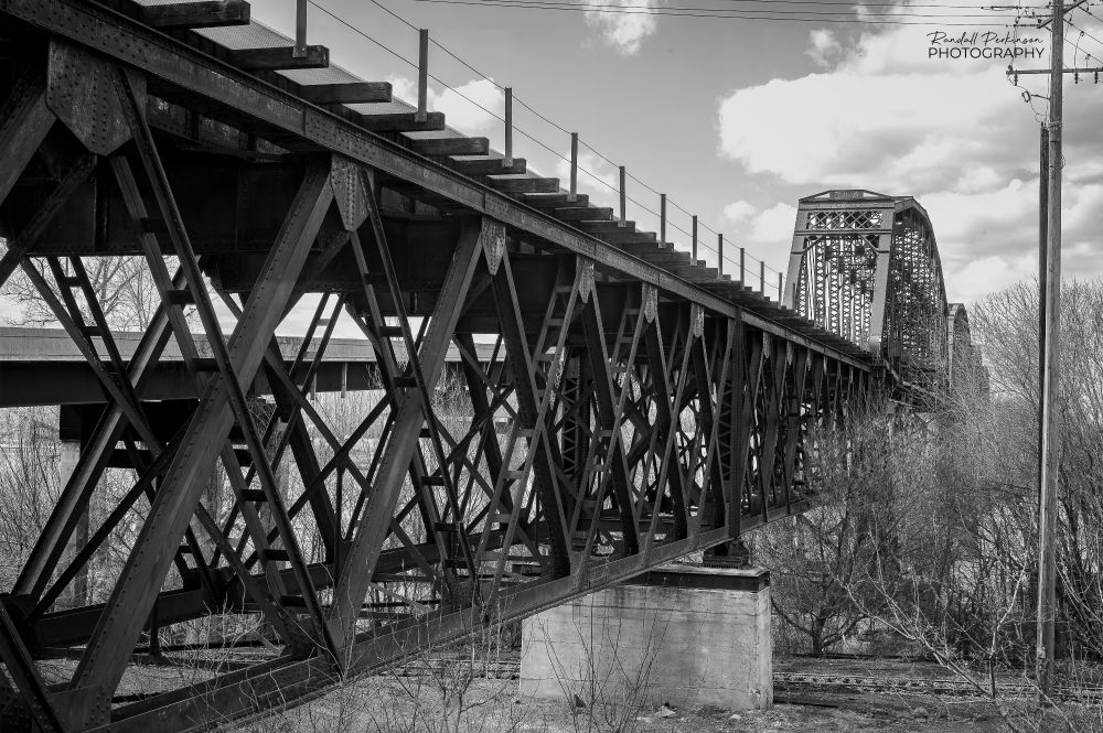 Steel truss railroad bridge approach span with main spans in the background.