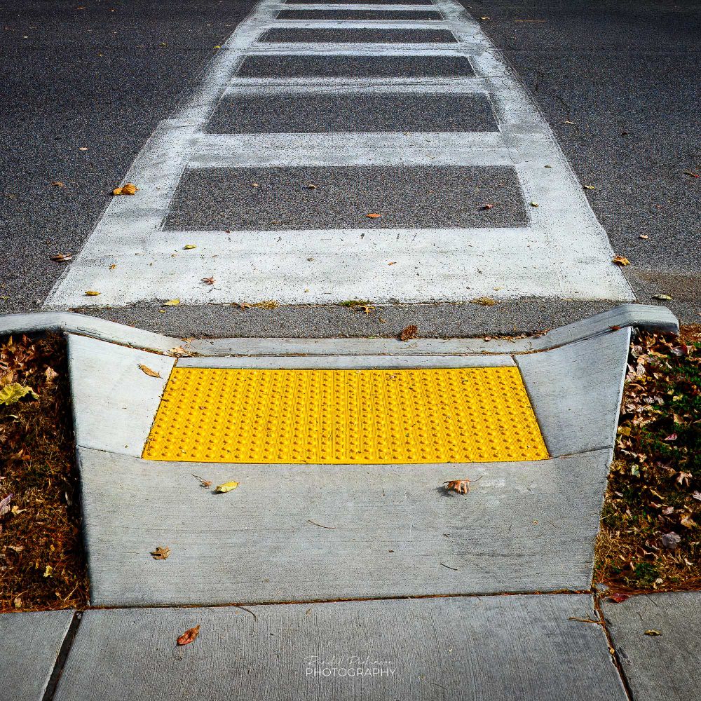 A transition ramp from a sidewalk to a street crosswalk includes a bright yellow detectable warning surface for the blind and visually impaired.