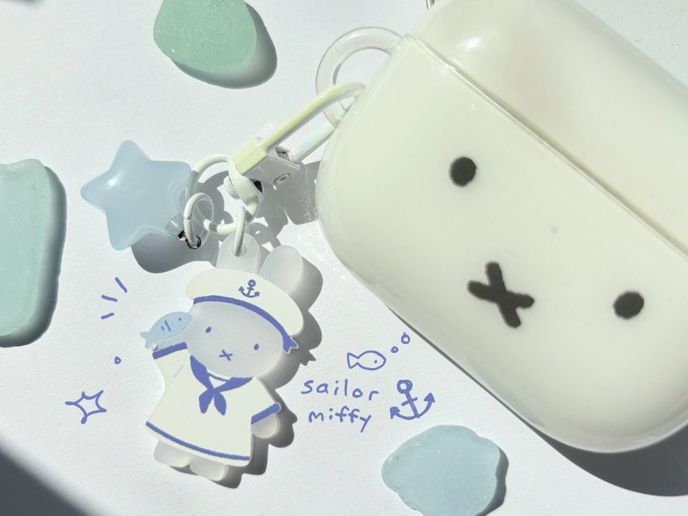 a frosted sailor miffy attached to a miffy airpod case. surrounded by sea glass