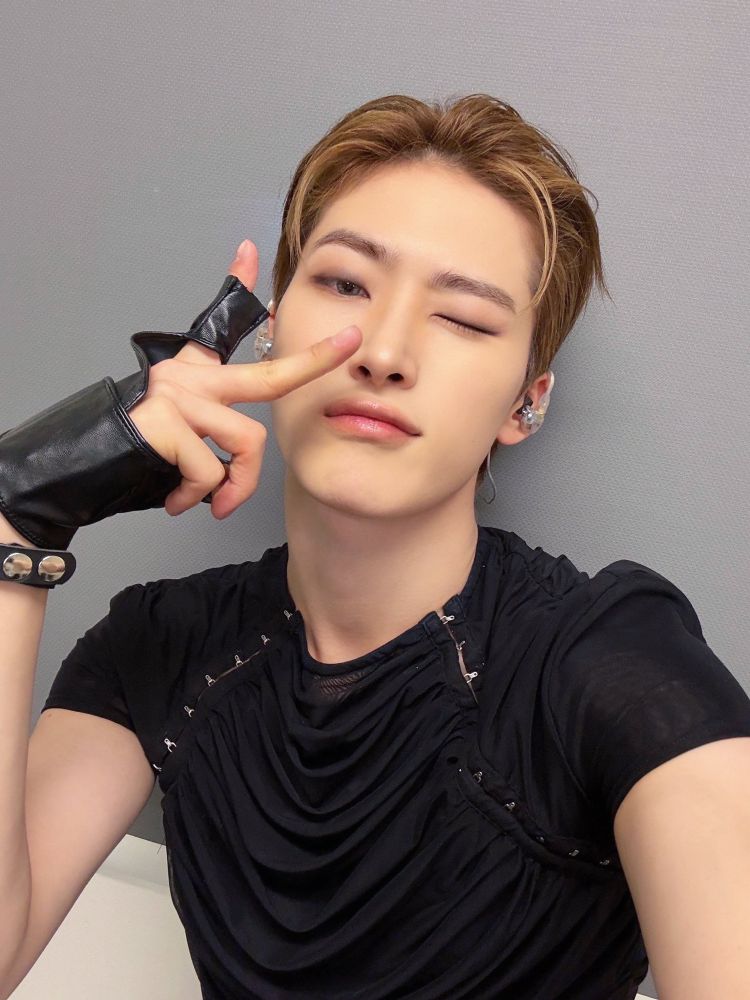 all(h)ours youmin selfie! he has light brownish gingerish something hair! and he’s wearing a black tee with black fingerless gloves. he’s winking at the camera and holding a peace sign 