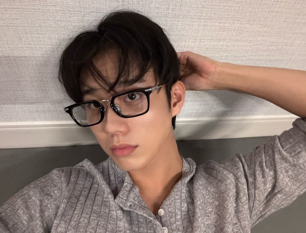 p1harmony intak looking like a hot sexy nerdy boy. he’s wearing a what looks to be 3/4 sleeve grey henley style top. 