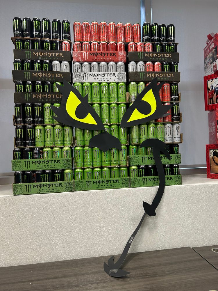 a monster energy drink display of the grinch wearing a christmas hat… his evil smile is falling off 