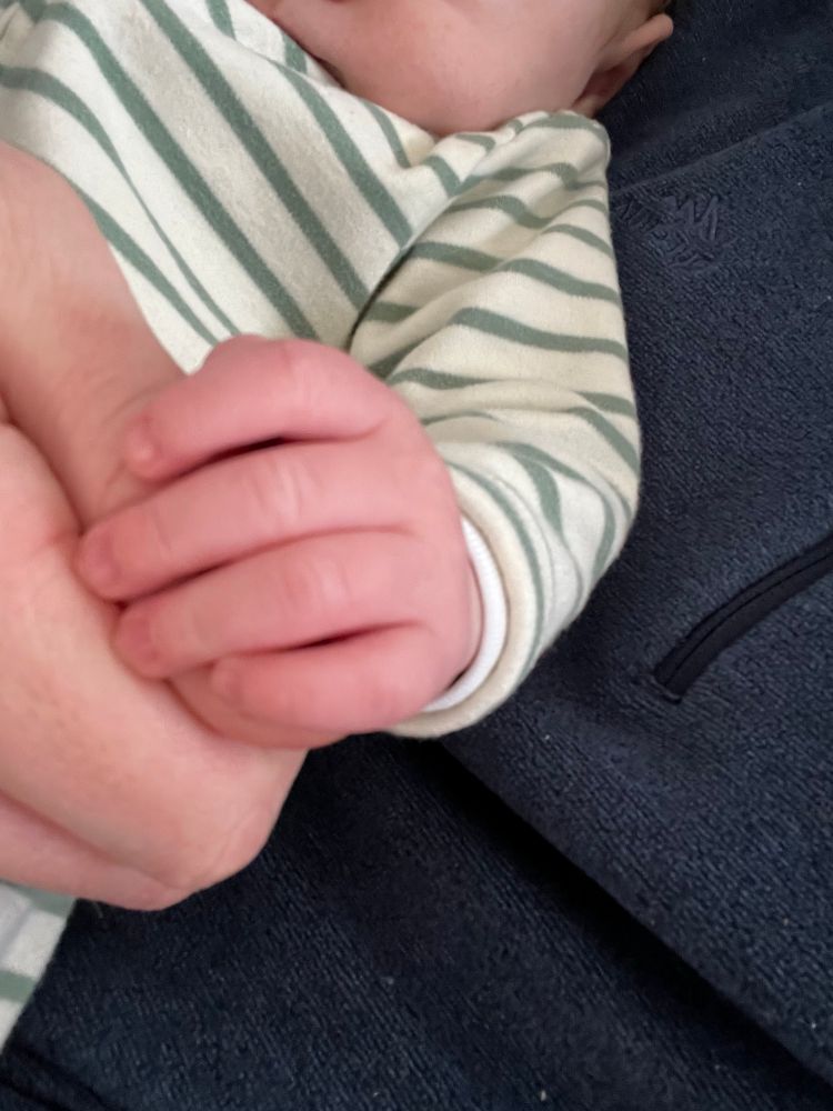 Photo d’une main de bébé tenant un pouce adulte
