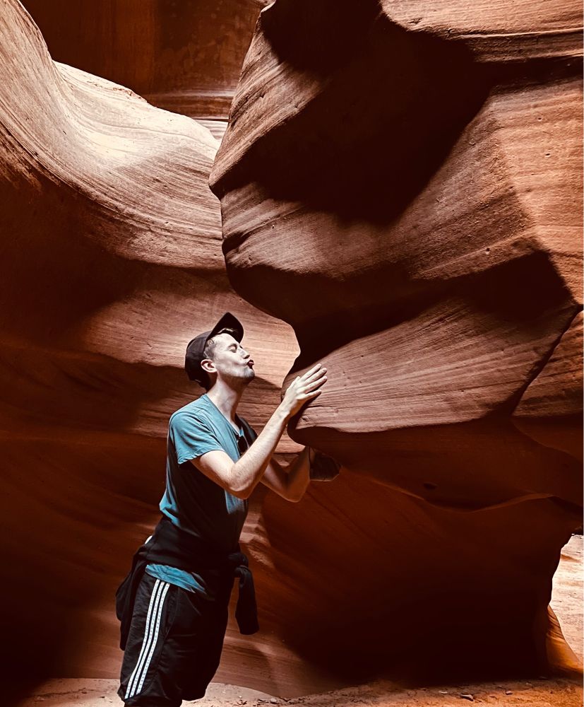 Luke preparing his lips for a kiss towards a rock shaped like a face in Antelope Canyon, Arizona.