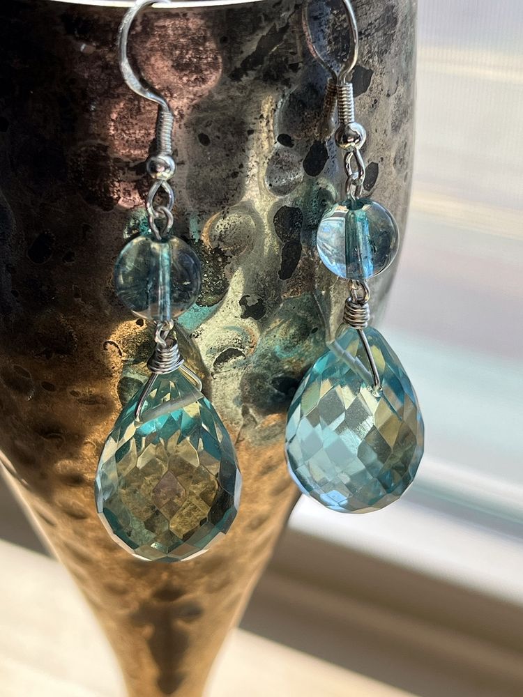 Dangle earrings: blue dyed quartz round beads above clear faceted aqua crystal briolettes, hanging from a pewter cup